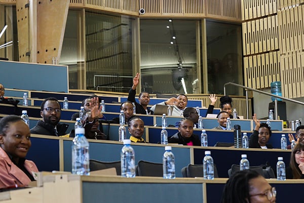 UP Mastercard Foundation Scholars seated in a lecture room, with some raising their hands to speak