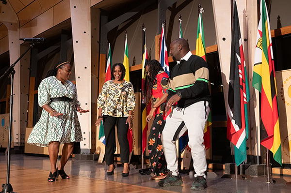 Tanzanian fellows celebrate by dancing on stage at an Africa dinner.